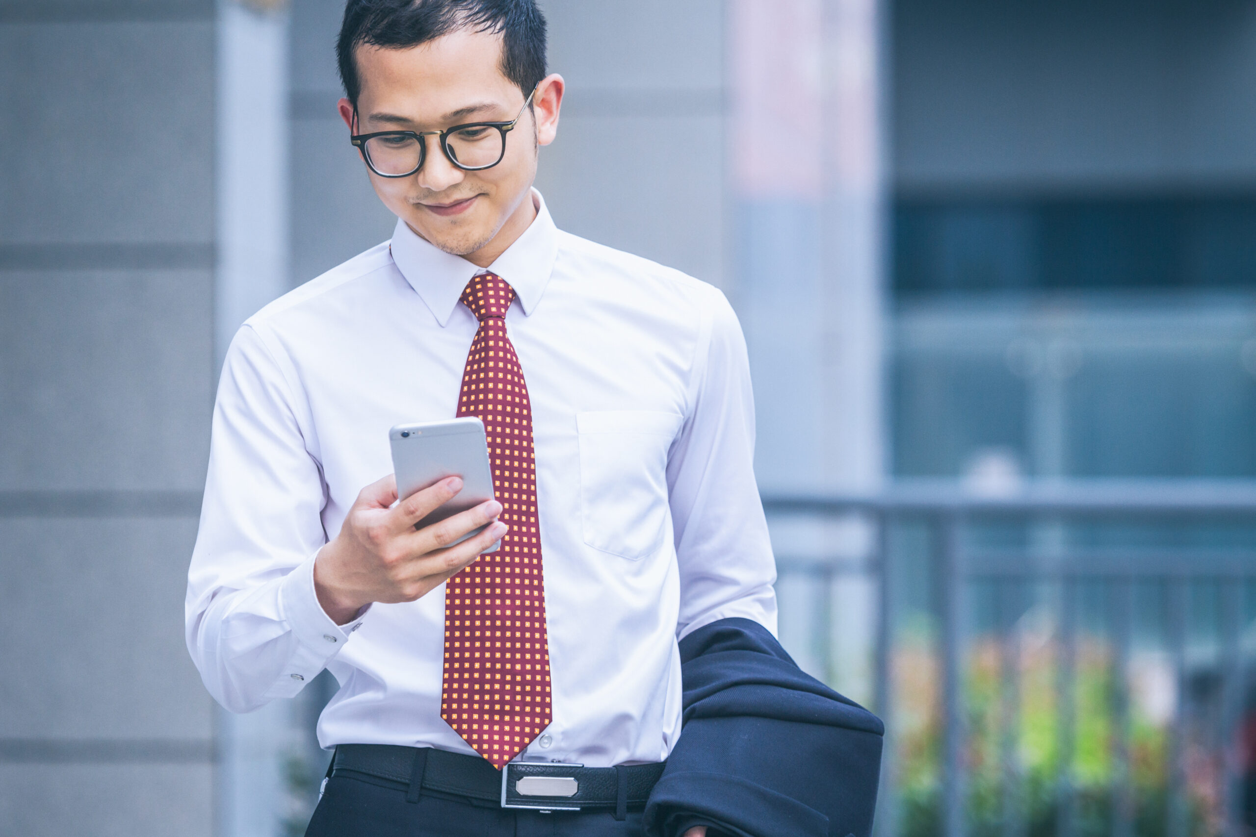 young businessman walking outside office,using his celephone.